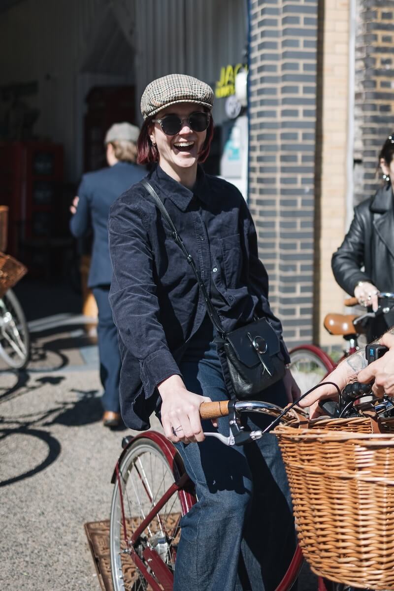 A smiling girl in a tweed flat cap ready for a cycle tour of London with Tally Ho 