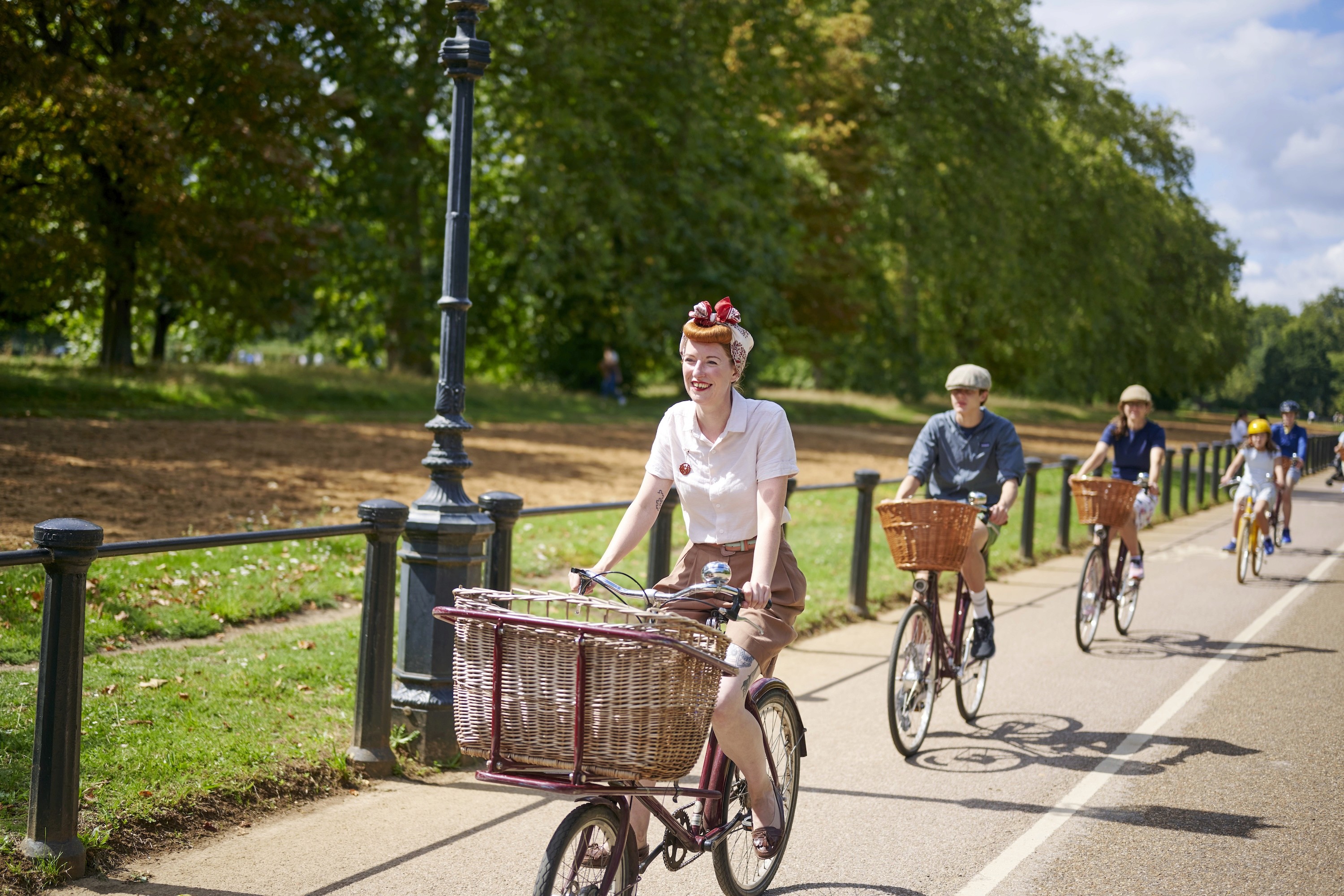 A family cycles through Hyde Park on vintage bicycles. 