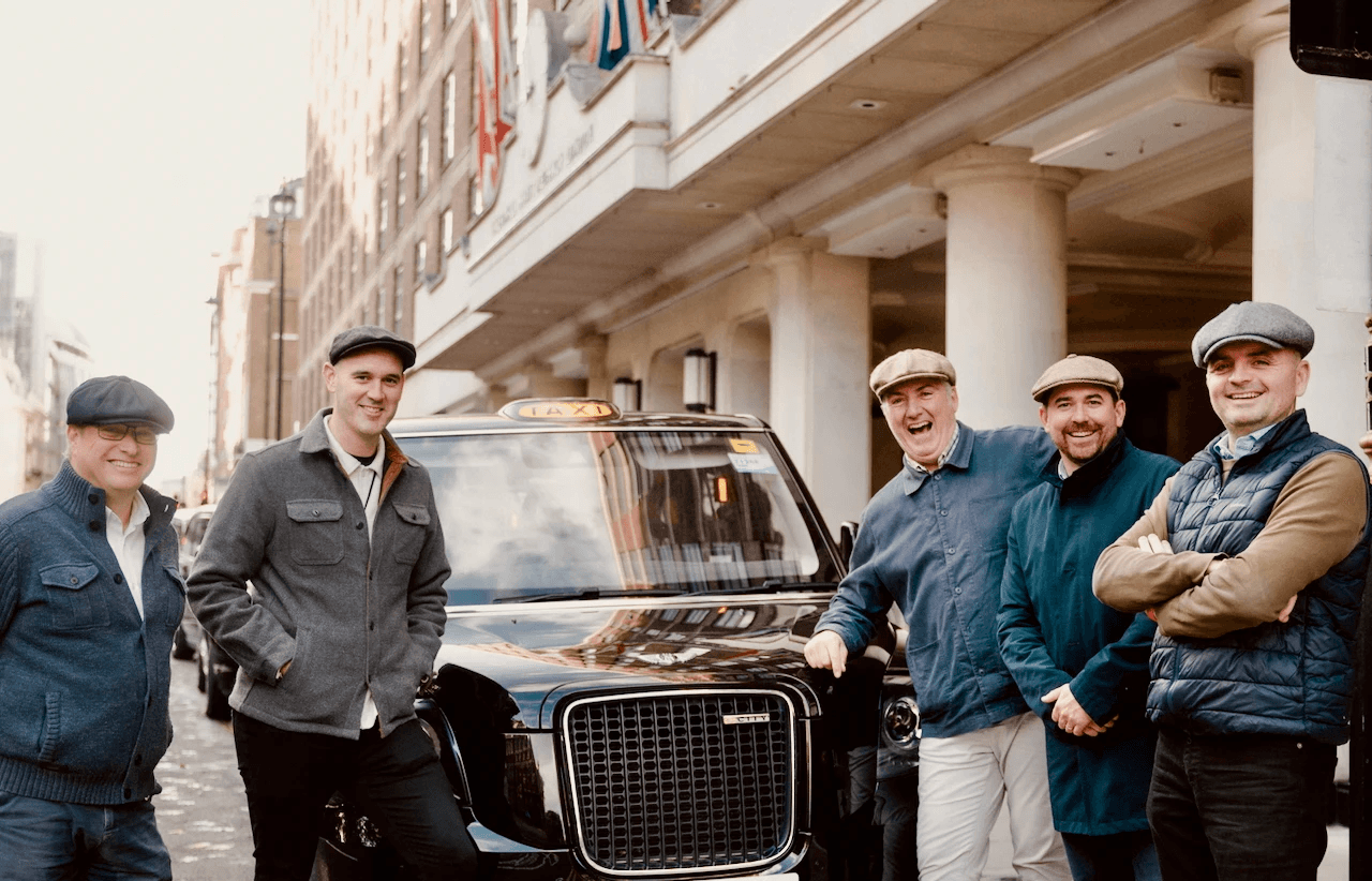 Smiling London taxi tour drivers in front of a black cab