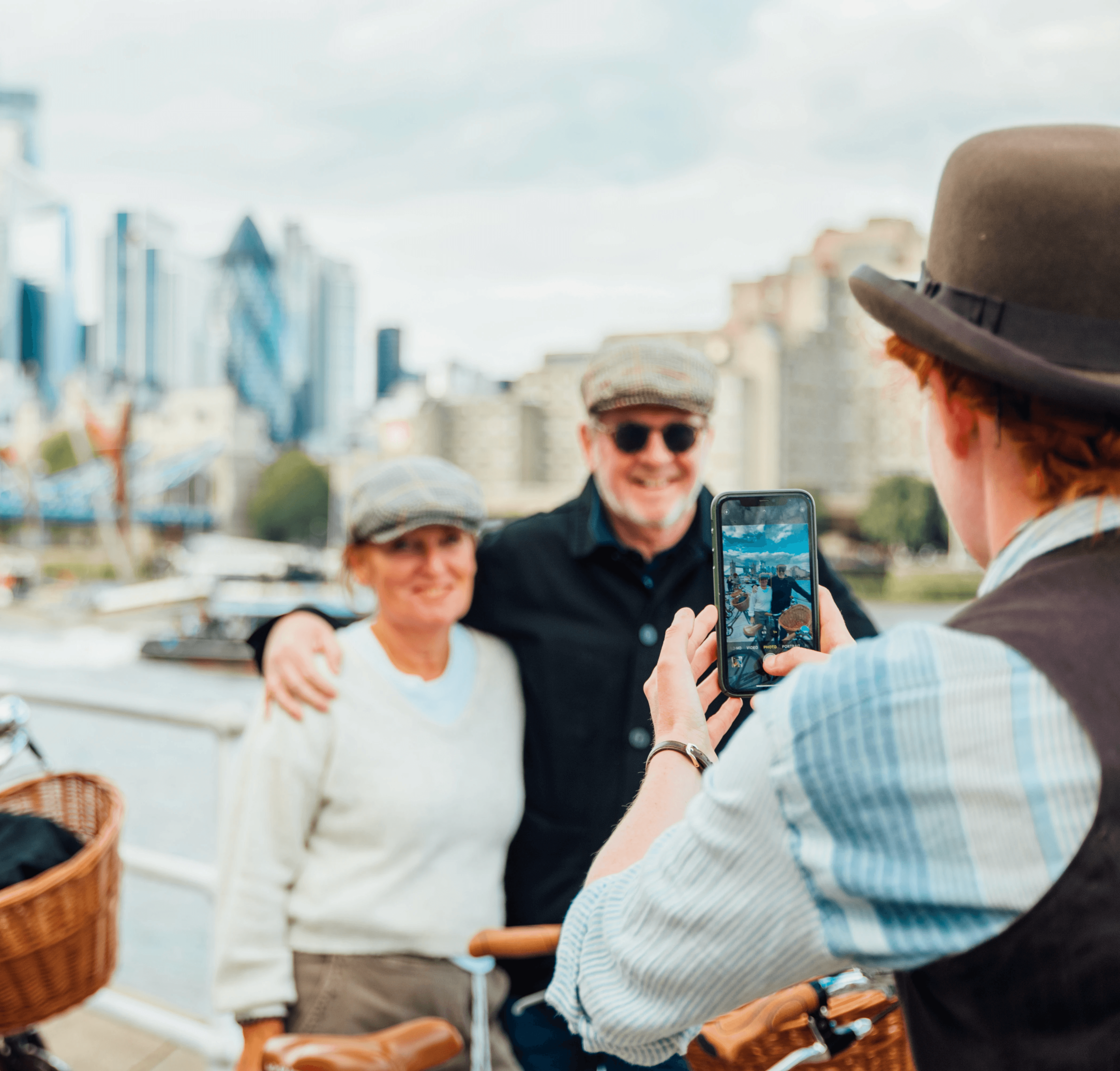 A couple wearing tweed caps pose for a photograph with Tower Bridge on a Tally Ho bike tour 