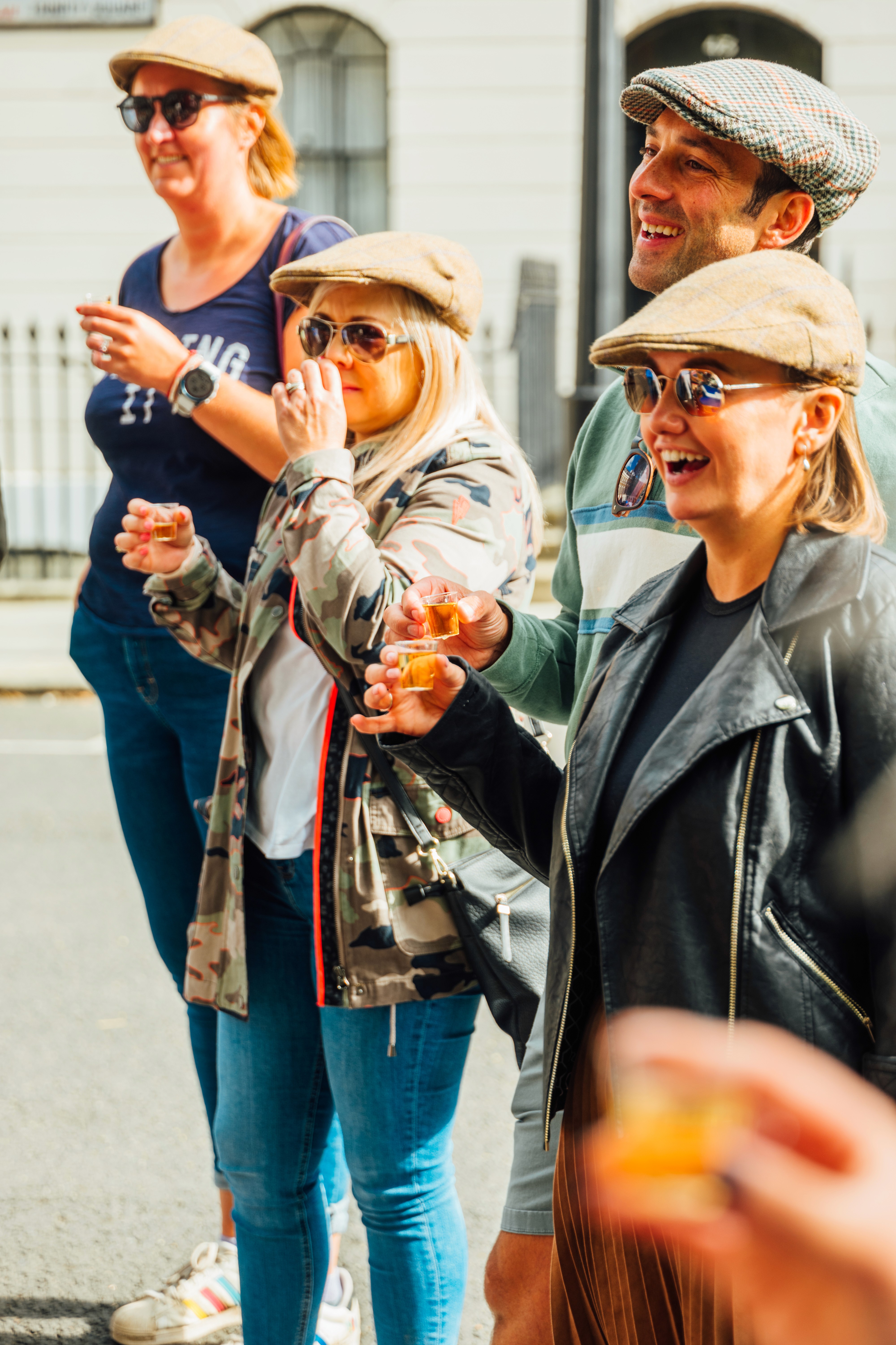 People wearing tweed caps and sampling gin on a bike tour of London