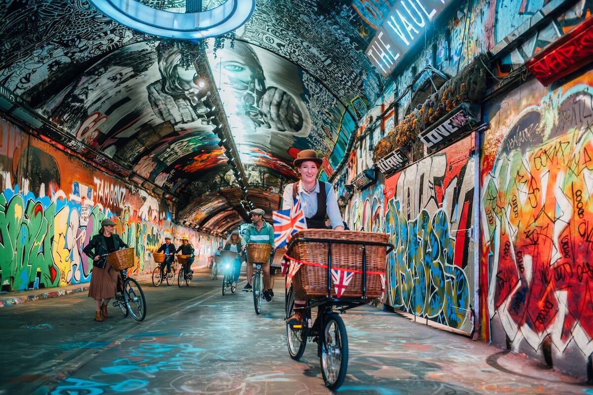 A Tally Ho London bike tour guide leading riders through a colourful graffiti tunnel in Waterloo 
