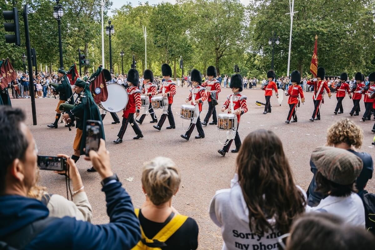 Spectators watching the Changing of the Guard parade with a marching band and soldiers in red uniforms and bearskin hats during our London bike tour