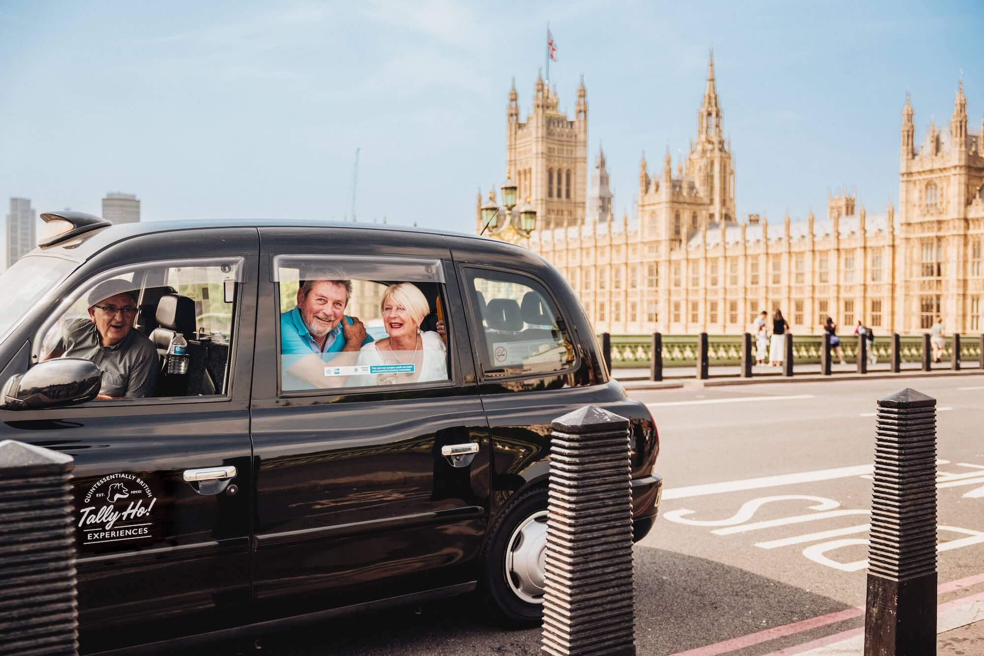 An iconic black taxi shows a couple of smiling tourists the London sights 