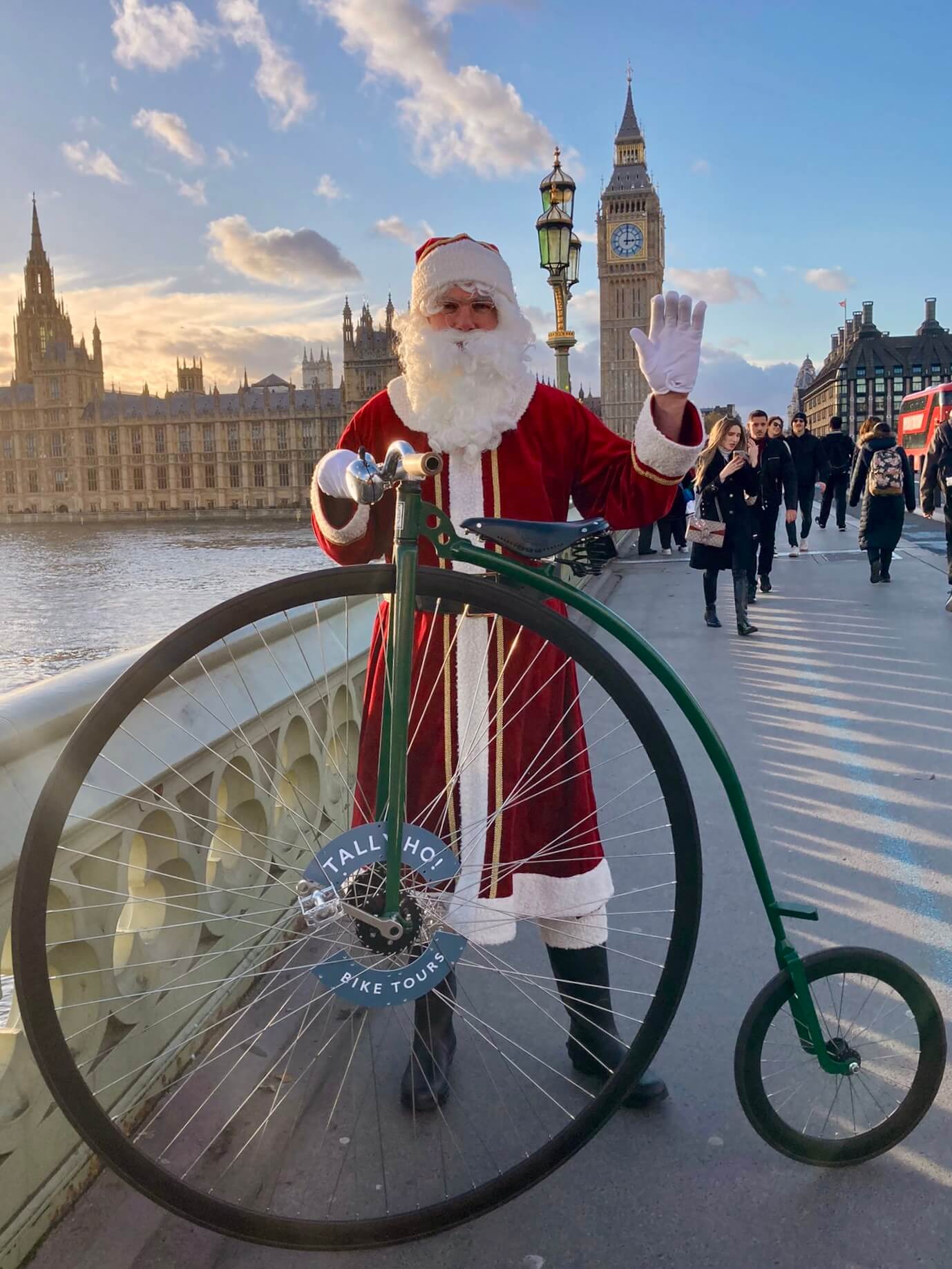 Santa with a penny farthing waving in front of Big Ben. Tally Ho London!