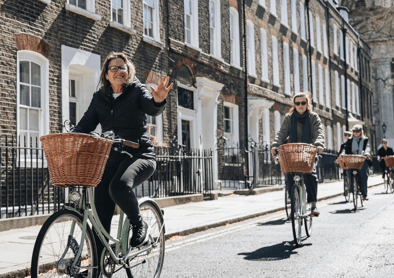 A woman waves while riding a vintage bicycle through the back streets of London 